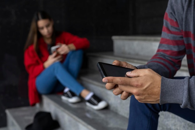 Young woman 23 Latin American sitting on the stairs checking her cell phone Selective focus on man's hands and cell phone Technology concept