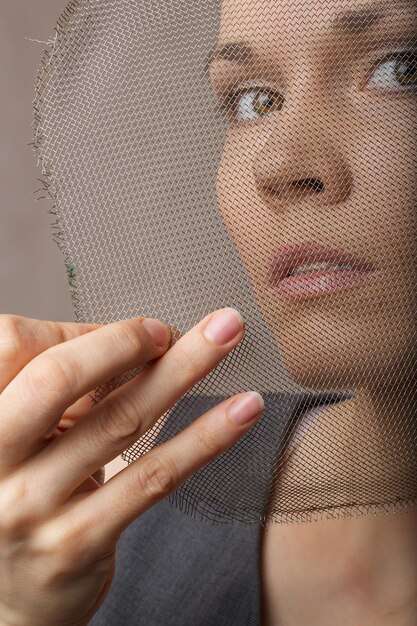 Foto giovane donna tra i 30 ei 40 anni, vestita con un abito grigio su sfondo grigio. avvicinamento