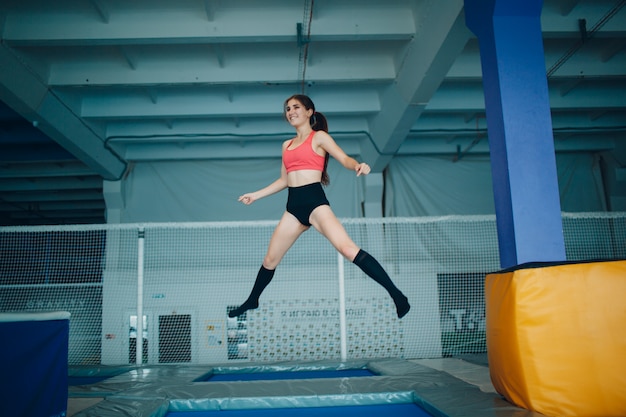 Acrobata della giovane donna che salta su un trampolino