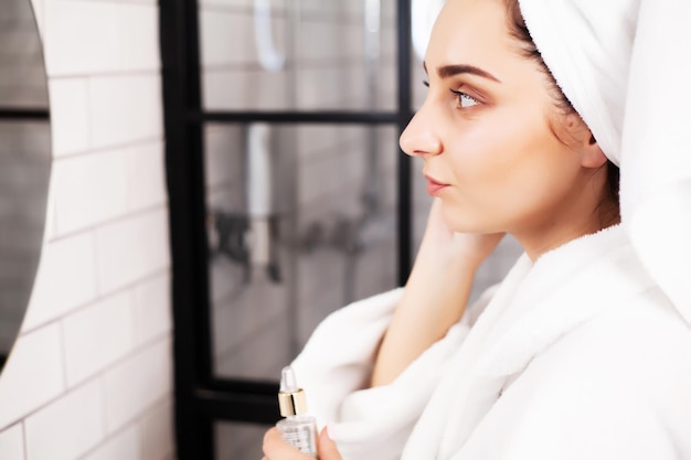 Young woman after shower going to apply skincare product oil or serum