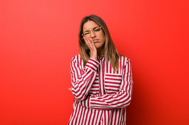 Young woman against a wall who is bored, fatigued and need a relax day.