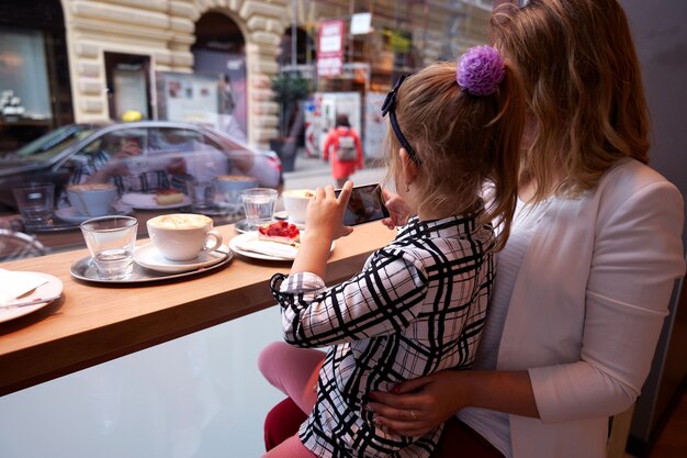 若い女性と小さな女の子が窓から写真を作る