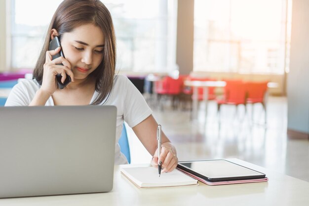 写真 教室に座っている若い女性が携帯電話に答えています