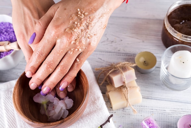 Young woman applies a coffee scrub on hands