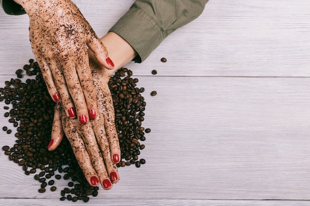 Young woman applies a coffee scrub on hands