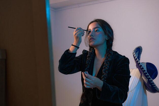 Young woman applies makeup in front of a mirror