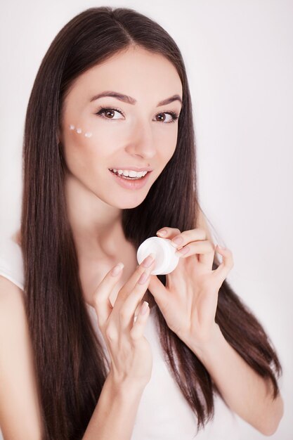 Young woman applies moisturizer on face