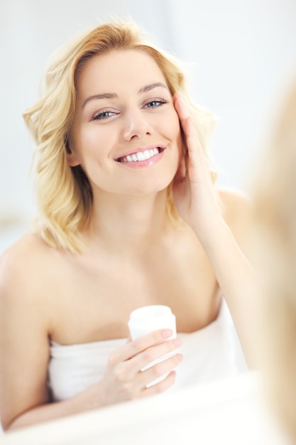 young woman applying cream in the bathroom
