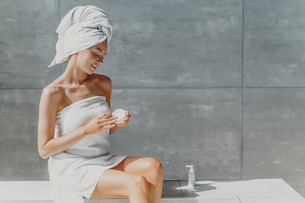 Young woman applying cream for spa treatment