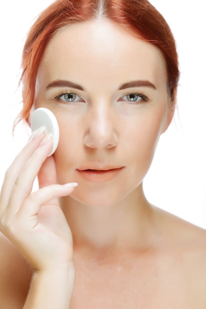 Young woman applying a creme on her face