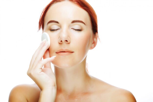  young woman applying a creme on her face