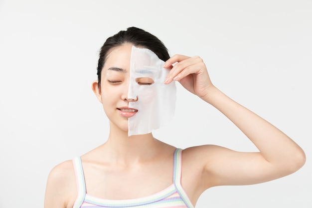 Young woman applying facial mask