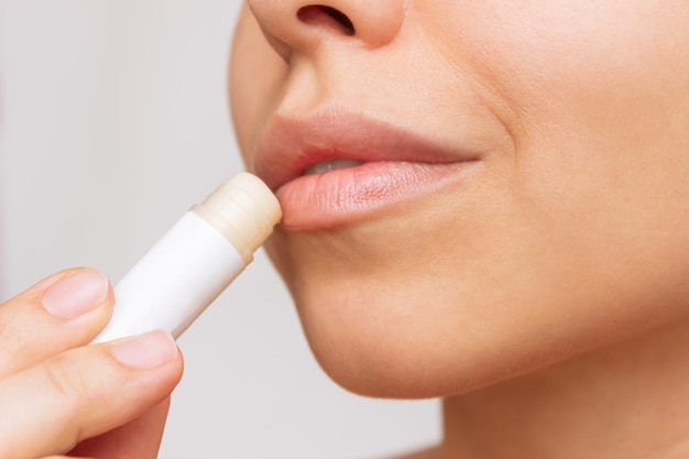 A young woman applying a hygienic lipstick on her lips Moisturizing chapstick for dry lips