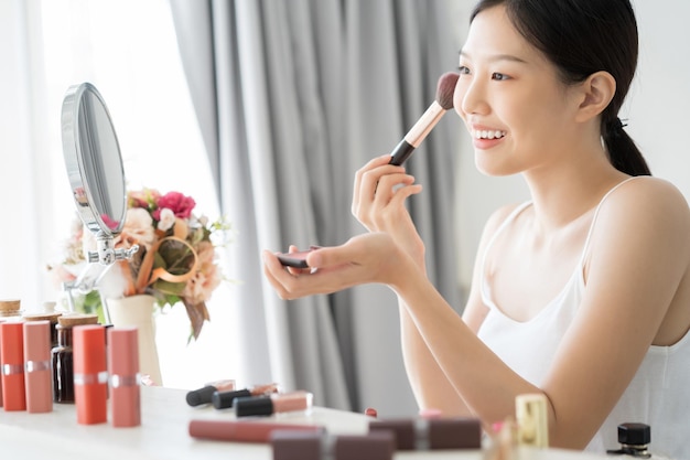 Photo young woman applying make-up at home