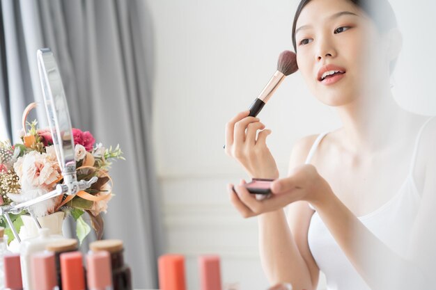 Photo young woman applying make-up at home