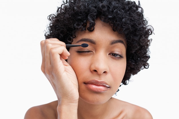 Young woman applying make-up while putting on eye-shadow 