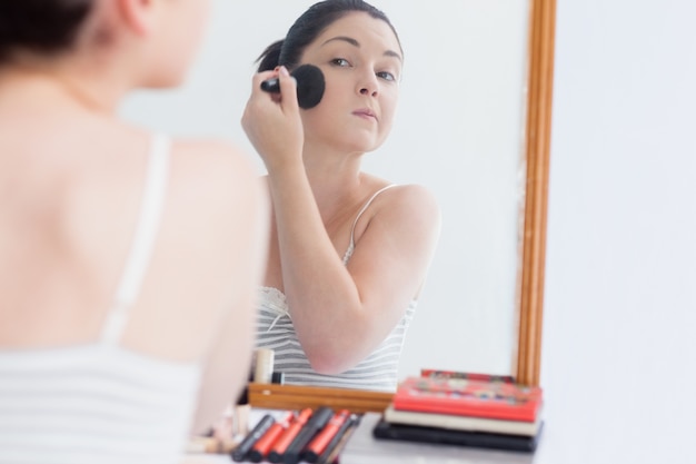 Young woman applying makeup on face