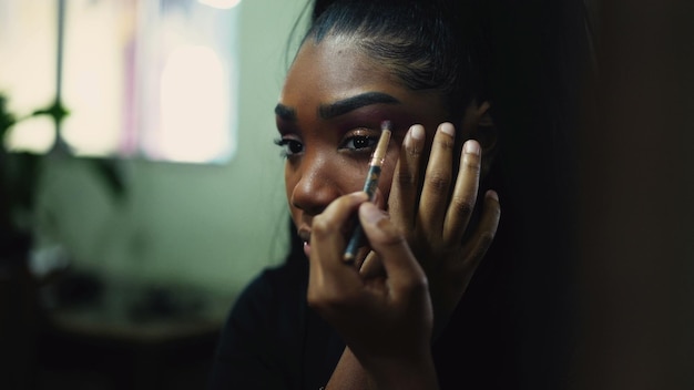 A young woman applying makeup in front of mirror