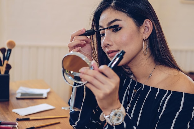 Young woman applying mascara at home