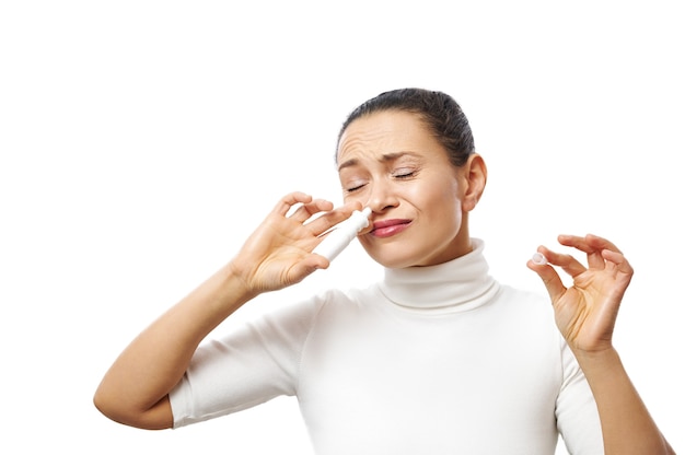 Photo young woman applying nasal spray posing at camera isolated on white surface with copy space