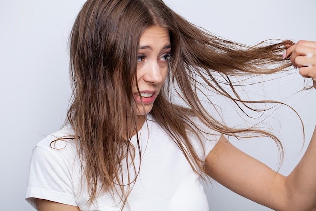 Giovane donna che applica olio essenziale organico naturale sui capelli