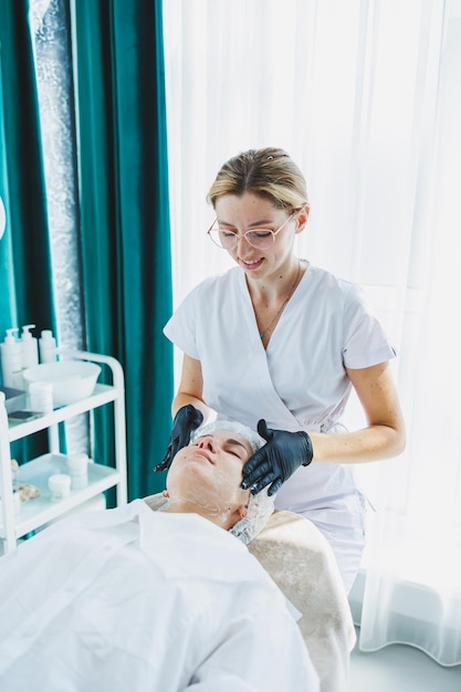 A young woman at an appointment with a beautician A cosmetologist gives a face massage to her client Facial A trip to the beautician