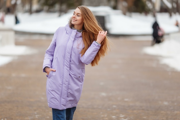 若い女性がウィンターパークを歩いています。雪の中のウィンターパーク。