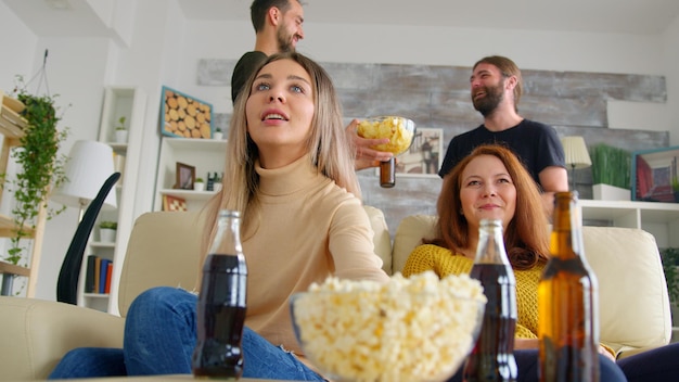 Молодая женщина приходит с пиццей в дом своих друзей, чтобы посмотреть футбольный матч.