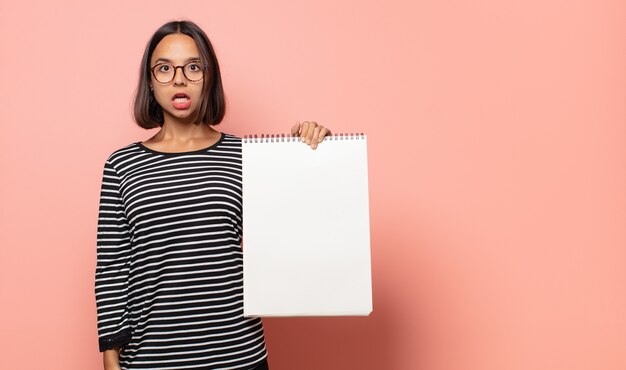 Young woman artist looking very shocked or surprised, staring with open mouth saying wow