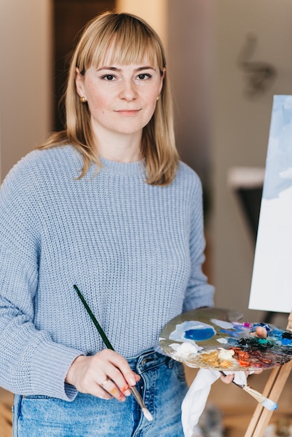 Молодая женщина-художник рисует картину в студии