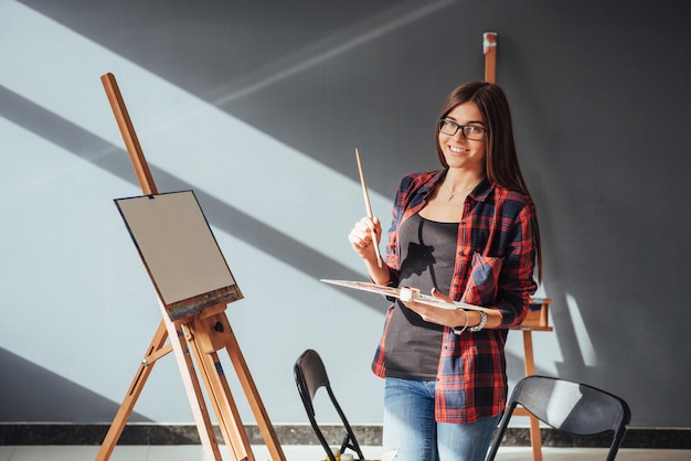 Художник молодой женщины рисует картину