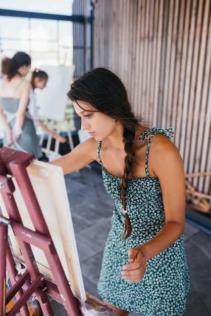 Young woman artist paints with a spatula on the canvas