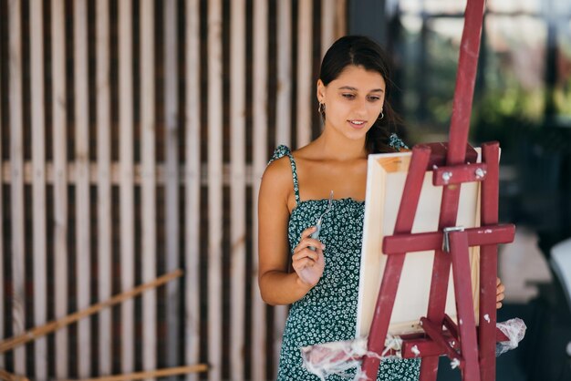 Young woman artist paints with a spatula on the canvas