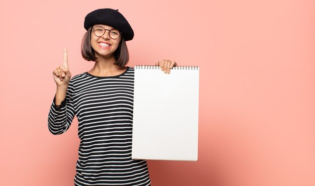 젊은 여성 예술가 미소하고 친절하게보고, 앞으로 손으로 번호 하나 또는 첫 번째 표시, 카운트 다운