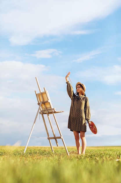 A young woman artist with an outdoor molbert in a warm summer evening