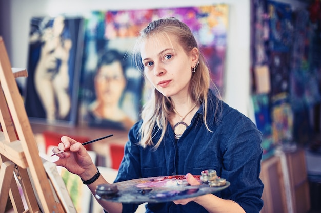 young woman artist working on painting in studio.