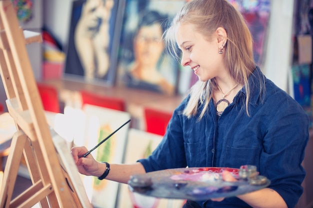 young woman artist working on painting in studio.