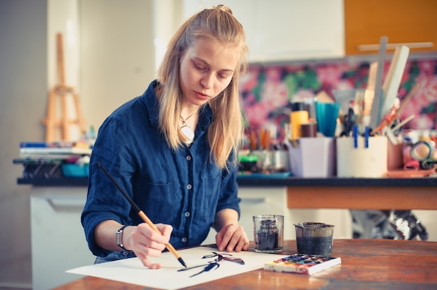 young woman artist working on painting in studio.