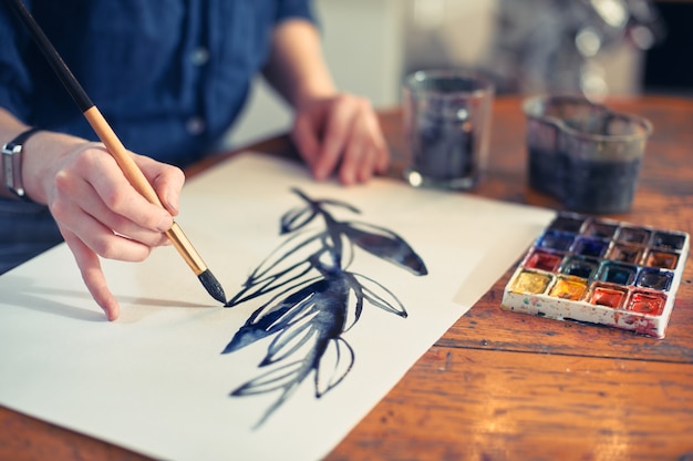 Photo young woman artist working on painting in studio.