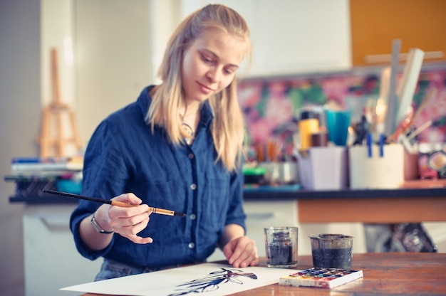 young woman artist working on painting in studio.
