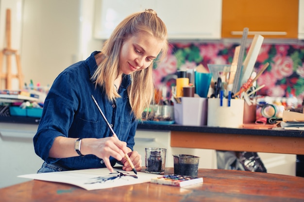 young woman artist working on painting in studio.
