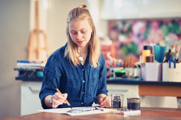 Young Woman Artist Working On Painting In Studio.