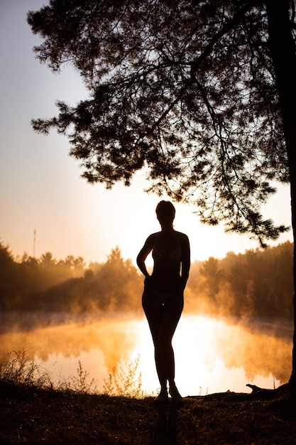 Young woman as silhouette by the sea