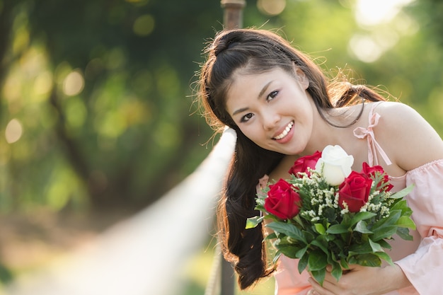 Ragazza asiatica della giovane donna con il luppolo sorridente rosso delle rose