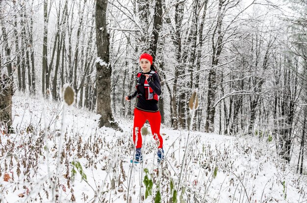 Молодая спортсменка в красных леггинсах бежит в зимнем лесу Зимние виды спорта Экстремальный бег
