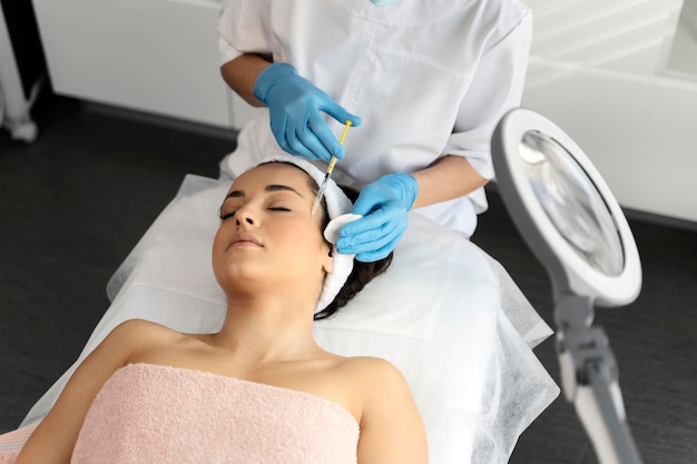 Young woman attending beautician having antiaging injection at her face