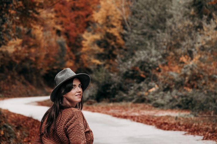 Photo young woman in autumn clothes on empty road through forest