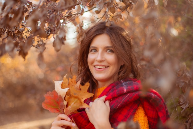 주황색 스웨터를 입은 가을 공원의 젊은 여성