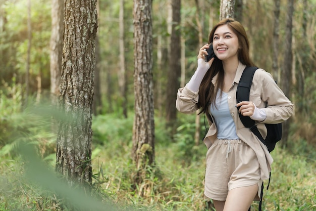 Young woman backpacker talking with mobile phone in the forest