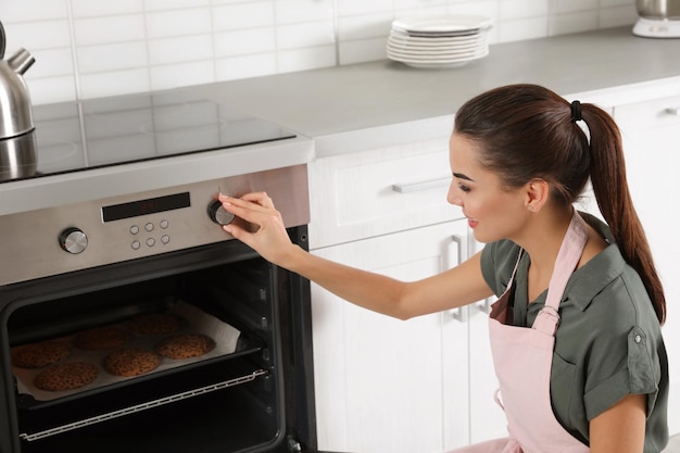young woman baking cookies in oven at home